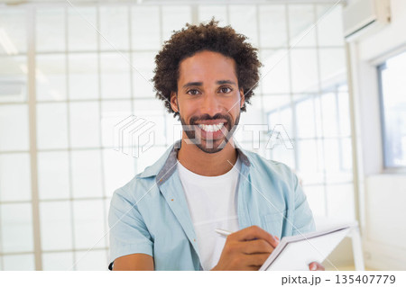 Mid adult African American man in blue shirt standing in office holding tablet and stylus smiling 135407779