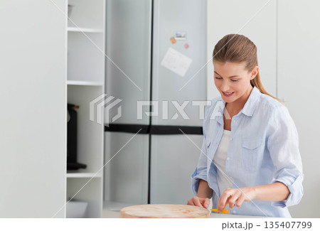Woman slicing yellow bell pepper with kitchen knife on cutting board in kitchen, copy space Woman slicing yellow bell pepper with kitchen knife on cutting board in kitchen, copy space 135407799