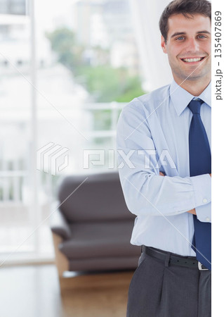 Male office worker standing arms crossed in office lounge by sofa, curtains, windows, copy space 135407869