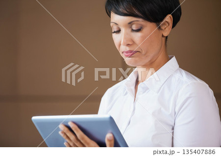 Businesswoman wearing white shirt holding tablet while reading data at office partition wall 135407886