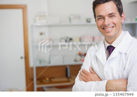Male doctor wearing lab coat and purple necktie in exam room with supply shelves, copy space Male doctor wearing lab coat and purple necktie in exam room with supply shelves, copy space 135407949