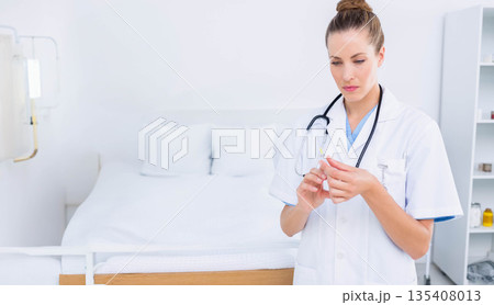 Woman doctor preparing syringe beside hospital bed in examination room with IV stand, copy space 135408013