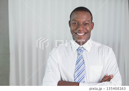 African American businessman standing before curtain wearing white shirt and light blue striped tie 135408163
