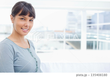 Woman sitting on white sofa in lounge overlooking city skyline through glass railing, copy space 135408180