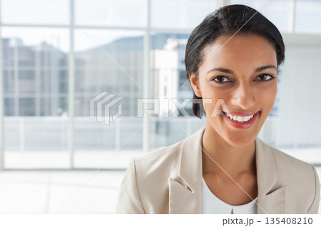 African American businesswoman standing before floor-to-ceiling glass windows at office, copy space 135408210