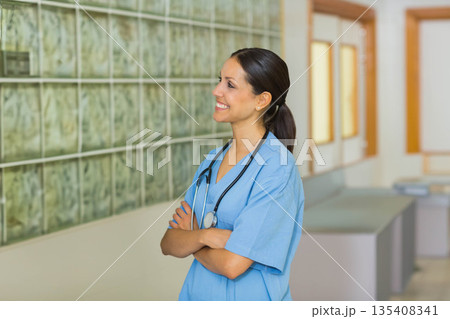 Female radiology tech viewing lightbox of X-ray films wearing stethoscope in hallway, copy space Female radiology tech viewing lightbox of X-ray films wearing stethoscope in hallway, copy space 135408341