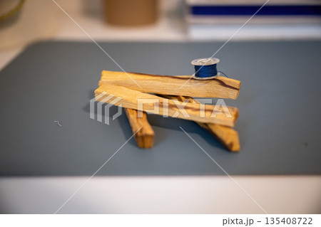 Minimal still life with wooden sticks and blue thread spool creating calm handmade craft composition Minimal still life with wooden sticks and blue thread spool creating calm handmade craft composition 135408722