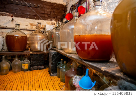 View of old fashioned wine cellar with glass storage for wine during fermentation process. 135409835