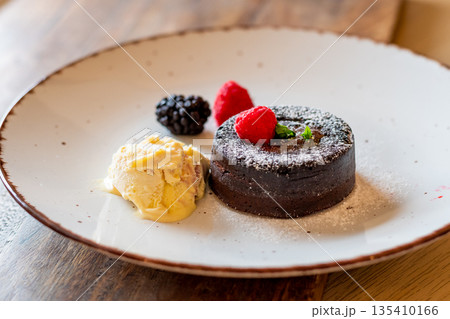 Chocolate fondant (cupcake) with raspberries, ice creme and powdered sugar placed on plate 135410166