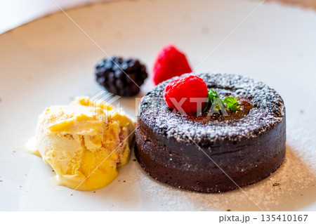 Chocolate fondant (cupcake) with raspberries, ice creme and powdered sugar placed on plate 135410167