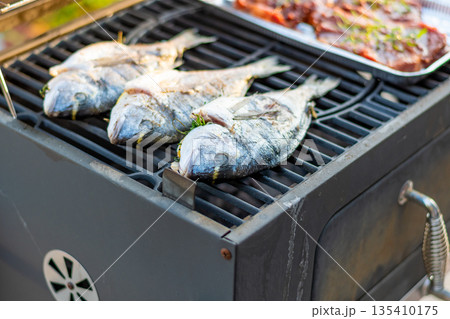 Sea bream dorado fish placed on the grill. Fresh sea food with herb and lemon. Summer bbq 135410175