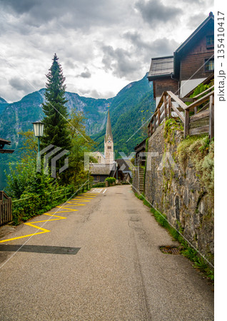 Famous Hallstatt city panorama with typical church near the Hallstatter see. Dramatic clouds on the sky. Famous tourist destination in Austria. Famous Hallstatt city panorama with typical church near the Hallstatter see. Dramatic clouds on the sky. Famous tourist destination in Austria. 135410417