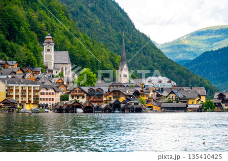 Famous Hallstatt city panorama with typical church near the Hallstatter see. Dramatic clouds on the sky. Famous tourist destination in Austria. 135410425