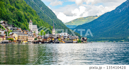 Famous Hallstatt city panorama with typical church near the Hallstatter see. Dramatic clouds on the sky. Famous tourist destination in Austria. 135410428