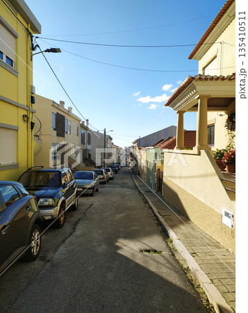 Experience the daily rhythm of a charming European neighborhood. This sunny street scene with yellow houses and parked cars is perfect for urban living and travelthemed designs. Experience the daily rhythm of a charming European neighborhood. This sunny street scene with yellow houses and parked cars is perfect for urban living and travelthemed designs. 135410511