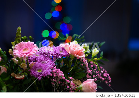 Bunch of gerbera flowers placed in front of christmas tree Bunch of gerbera flowers placed in front of christmas tree 135410613