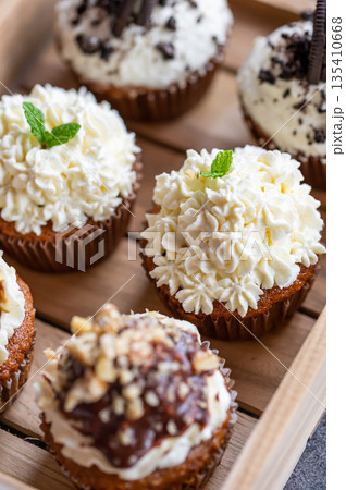 Cupcakes and muffins placed in wooden box. Chocolate and creme with nuts. Fresh home make baked sweets. Cupcakes and muffins placed in wooden box. Chocolate and creme with nuts. Fresh home make baked sweets. 135410668