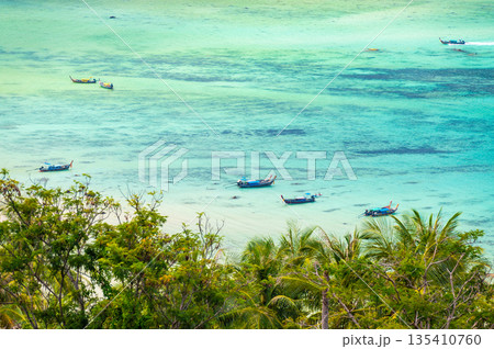 Long tail boats are parking at Tonsai pier, Ko Phi Phi islands, Thailand. Summer weather, concept of tropical vacation in paradise. Long tail boats are parking at Tonsai pier, Ko Phi Phi islands, Thailand. Summer weather, concept of tropical vacation in paradise. 135410760