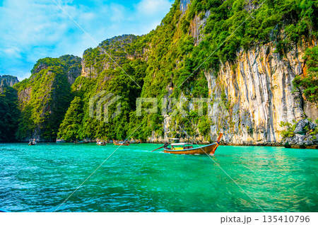View of Pi Leh lagoon (also known as Green Lagoon) at Ko Phi Phi islands, Thailand. View from typical long tailed boat. Typical Thai picture of tropical paradise. Limestone rock and turquoise water. View of Pi Leh lagoon (also known as Green Lagoon) at Ko Phi Phi islands, Thailand. View from typical long tailed boat. Typical Thai picture of tropical paradise. Limestone rock and turquoise water. 135410796