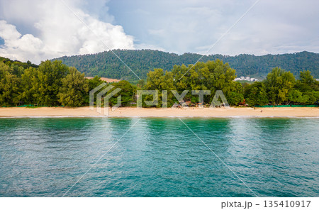 Aerial drone view of Koh Lanta island - the long beach. Famous tropical beach with white sand and turquoise ocean. The island mountains in background. 135410917