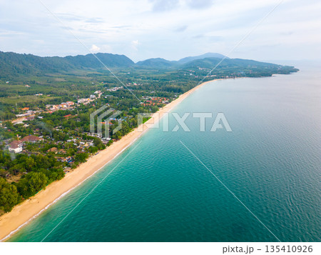 Aerial drone view of Koh Lanta island - the long beach. Famous tropical beach with white sand and turquoise ocean. The island mountains in background. Aerial drone view of Koh Lanta island - the long beach. Famous tropical beach with white sand and turquoise ocean. The island mountains in background. 135410926