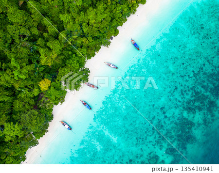 Aerial drone view of famous Monkey Beach at Ko Phi Phi island, Thailand. Tropical beach with white sand, turquoise water and green forest. Long tailed boats are waiting on beach. Exotic tourist 135410941