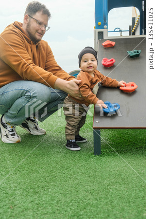 Father Assisting Toddler on Playground Climbing Wall Father Assisting Toddler on Playground Climbing Wall 135411025