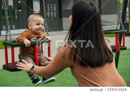 Mother and Baby on Swing in Playground 135411026