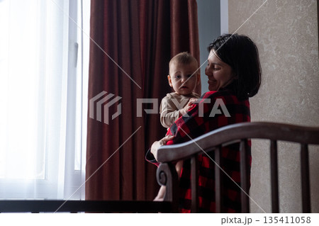 Mother Holding Baby in Dimly Lit Room 135411058