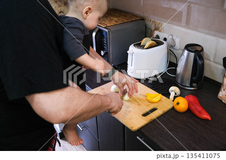 Parent cooking in kitchen with baby 135411075
