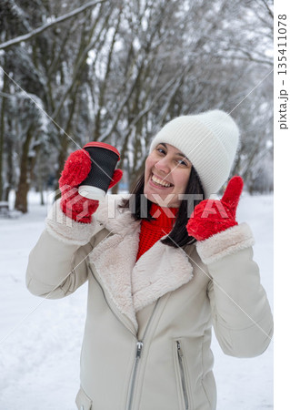 Woman Enjoying Coffee in Snowy Winter Park 135411078