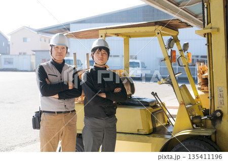 フォークリフトの前に立つ2人の作業員 135411196