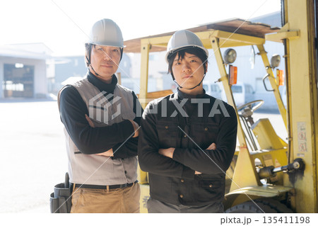 フォークリフトの前に立つ2人の作業員 フォークリフトの前に立つ2人の作業員 135411198