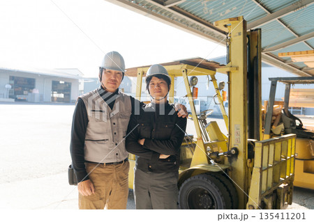 フォークリフトの前に立つ2人の作業員 135411201