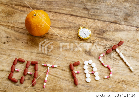 eat fast message with pills and half plate of food on table 135411414