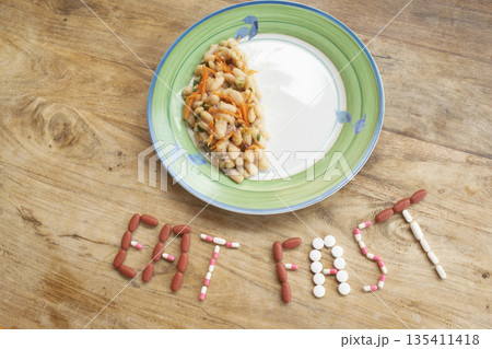 eat fast message with pills and half plate of food on table eat fast message with pills and half plate of food on table 135411418