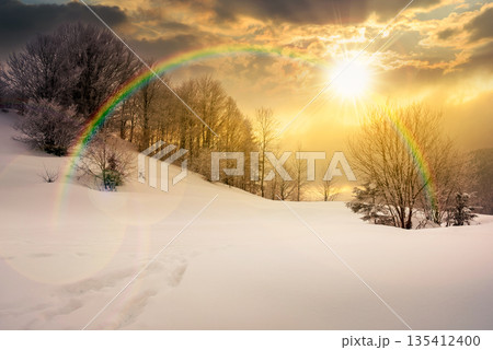 gorgeous winter landscape in mountains at sunset. beautiful trees in hoarfrost on snow covered hill in evening light. glowing overcast sky above the ridge. hope, expectation, new beginning and bright 135412400