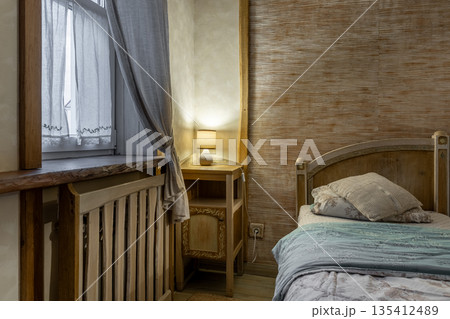Rustic bedroom detail with wooden bedside table and warm lamp Rustic bedroom detail with wooden bedside table and warm lamp 135412489