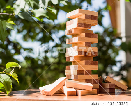 Wooden block tower on table with green tree background 135413385