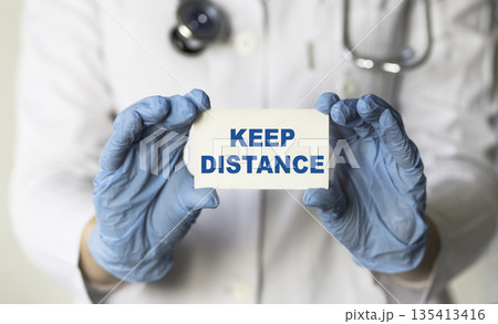 A doctor hold card in his hands with text KEEP DISTANSE, protect from Coronavirus or Covid-19 epidemic. Medicine concept 135413416