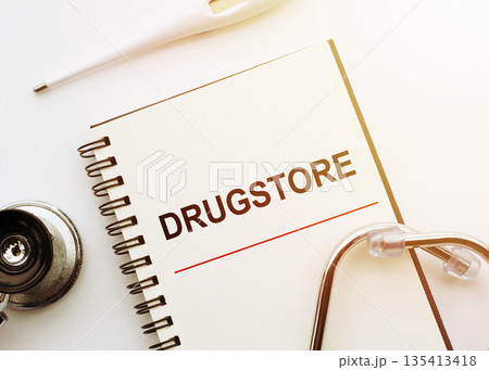 Medical concept. Notebook with word DRUGSTORE on white desk with stethoscope and thermometer. 135413418
