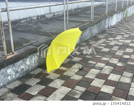 a yellow umbrella on the sidewalk 135414812