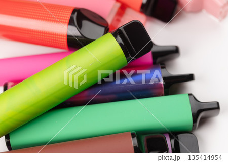 Close-up of colorful disposable electronic cigarettes and vapes on a white background. Close-up of colorful disposable electronic cigarettes and vapes on a white background. 135414954