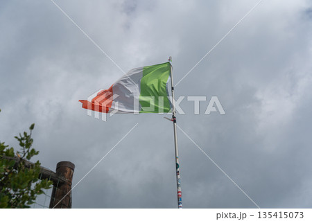 Italian national flag waving against cloudy sky. Symbol of Italy, patriotism, culture and European identity. 135415073