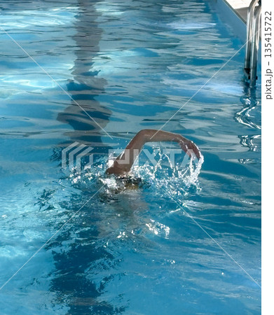 Swimmer Makes a Splash in Clear Pool Water While Doing Laps 135415722