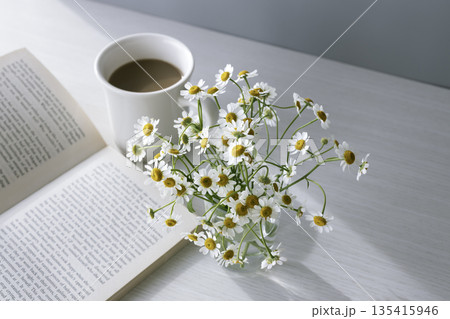 マトリカリアの花とカフェオレのある朝 本とテーブルの静物写真 マトリカリアの花とカフェオレのある朝 本とテーブルの静物写真 135415946