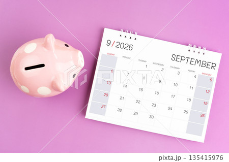 Desk calendar for September 2026 and pink piggy bank on purple background. 135415976