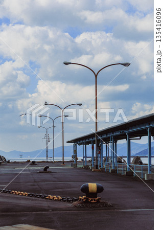 愛媛県八幡浜港の広角波止場 街灯と青空 山遠景の港湾空き風景 愛媛県八幡浜港の広角波止場 街灯と青空 山遠景の港湾空き風景 135416096