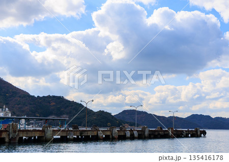 愛媛県八幡浜港の海上桟橋風景 街灯群と紅葉山 青空をバックにした港湾景観 135416178