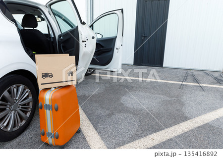 suitcases and boxes were lying on the ground next to the car. 135416892